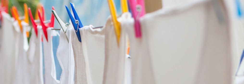 white tank tops on a clothes line with colorful clothespins