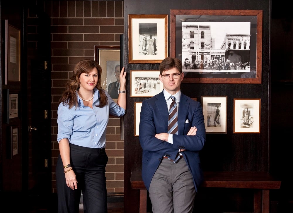 Kelly and David Hamilton standing in front of a wall of old photos