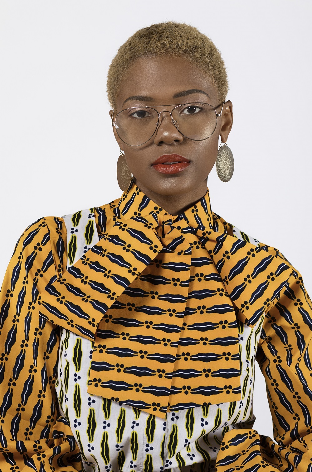 close up of a woman wearing glasses and an ankara print dress designed by Reuben Reuel