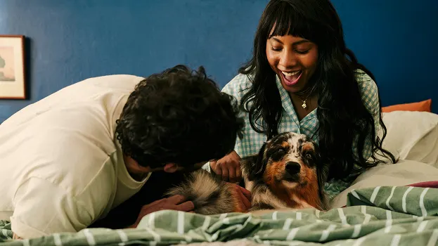 A couple relaxing on a bed with their dog, surrounded by soft cotton bedding.